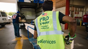 The header photograph features a person with a yellow vest loading construction materials into a truck.