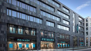 Photograph of a Primark store on the ground floor of a large gray brick building.