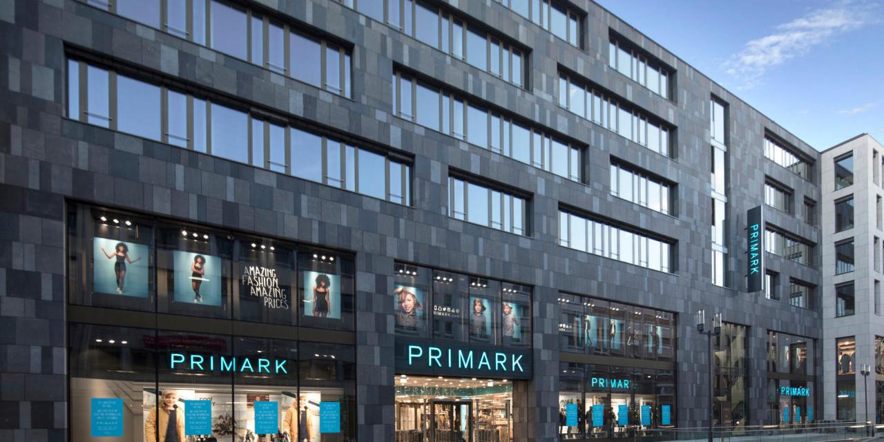 Photograph of a Primark store on the ground floor of a large gray brick building.