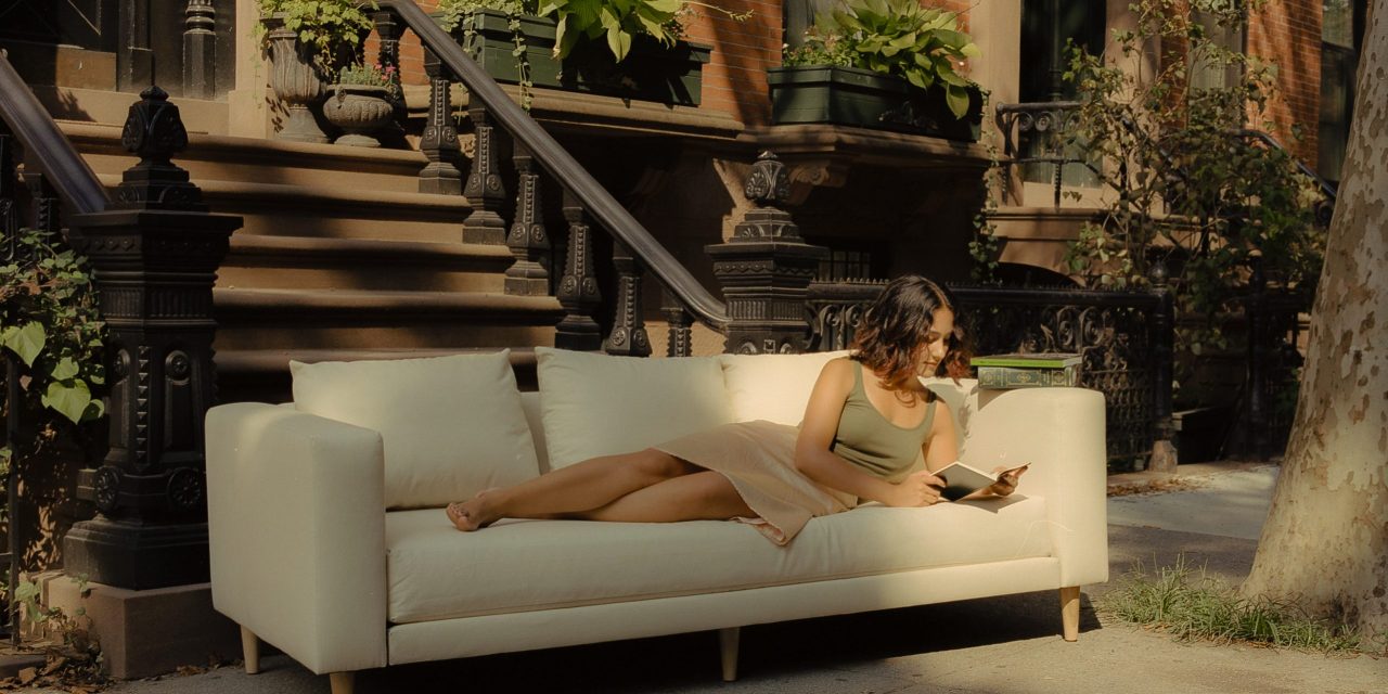 The header image shows a woman laying on a couch in the street.