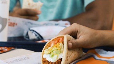 Photograph of a person holding a Taco Bell taco.