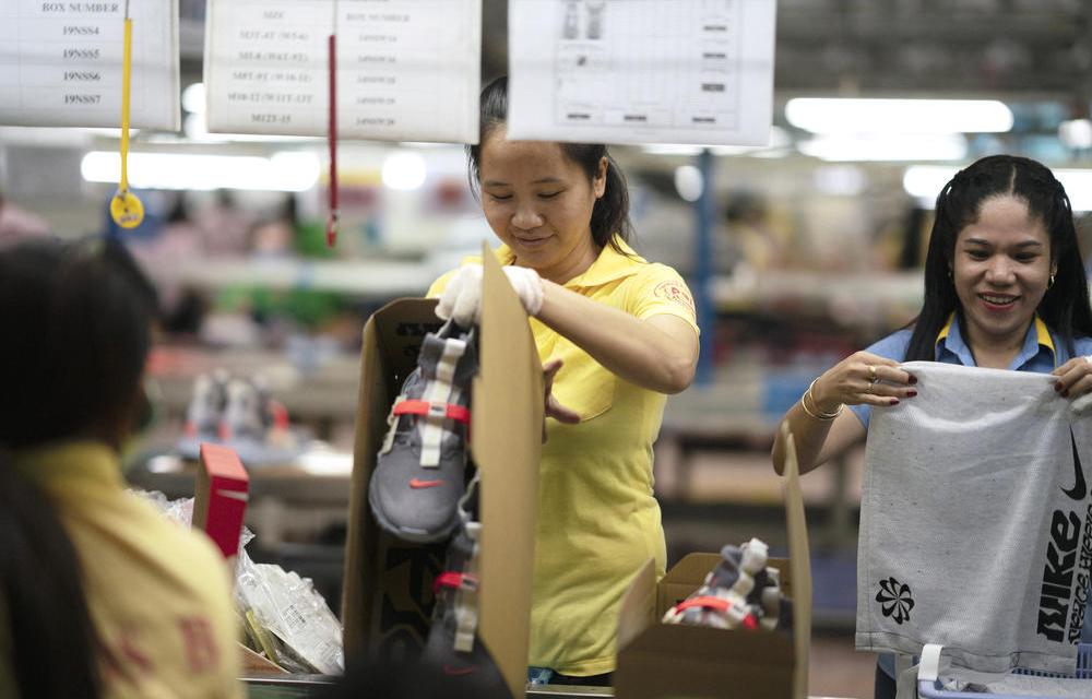 Photograph of a woman assembling Nike shoes in a factory.