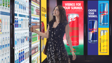Photograph of a woman shopping with soda ads behind her.
