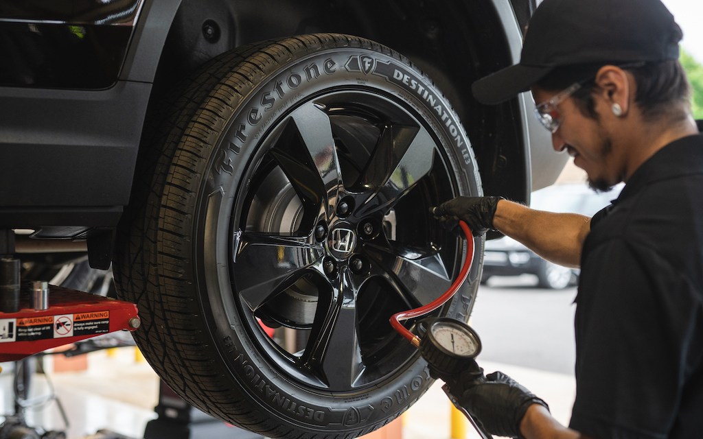 Photograph of a man changing a tire on a car.