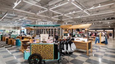 Mobile stands with t-shirts, totebags and other tchotchkes are displayed on a black-and-white checkered floor