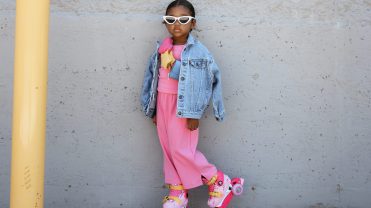Kids clothing model in hot pink dress, jean jacket and sun glasses