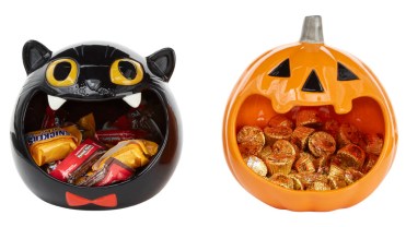 Pumpkin and cat-shaped candy bowls hold Reese's Peanut Butter Cups and Snicker's candy bars
