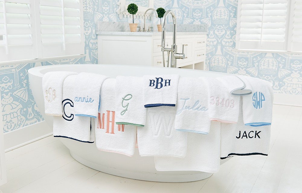 Embroidered towels draped over a white bath tub
