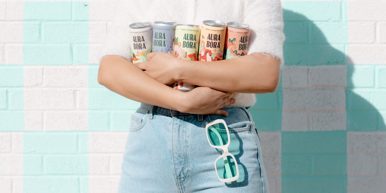 Person holds five cans of different Aura Bora sparkling water flavors