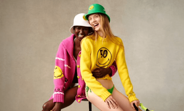 Two models in The Smiley Company apparel in pink, yellow, white and green