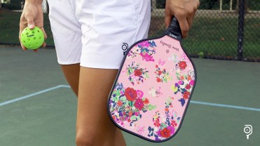 Model in white shorts holding a pickleball and a Vera Bradley paddle