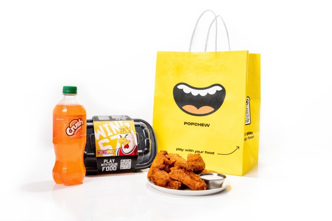 Chicken wings on a plate next to a yellow Popchew bag and orange crush soda