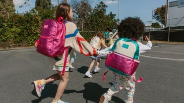 Two children holding hands wearing hot pink metallic backpacks
