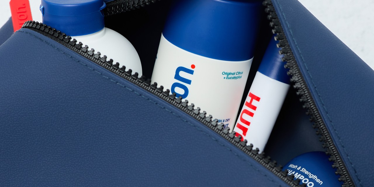 Blue toiletry bag with shampoo bottle, conditioner, deodorant and eye cream