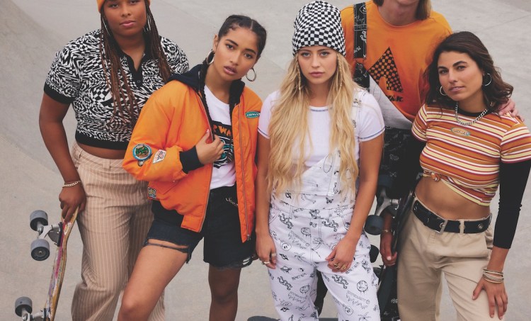 People in a skatepark holding skateboards while modeling orange-colored streetwear