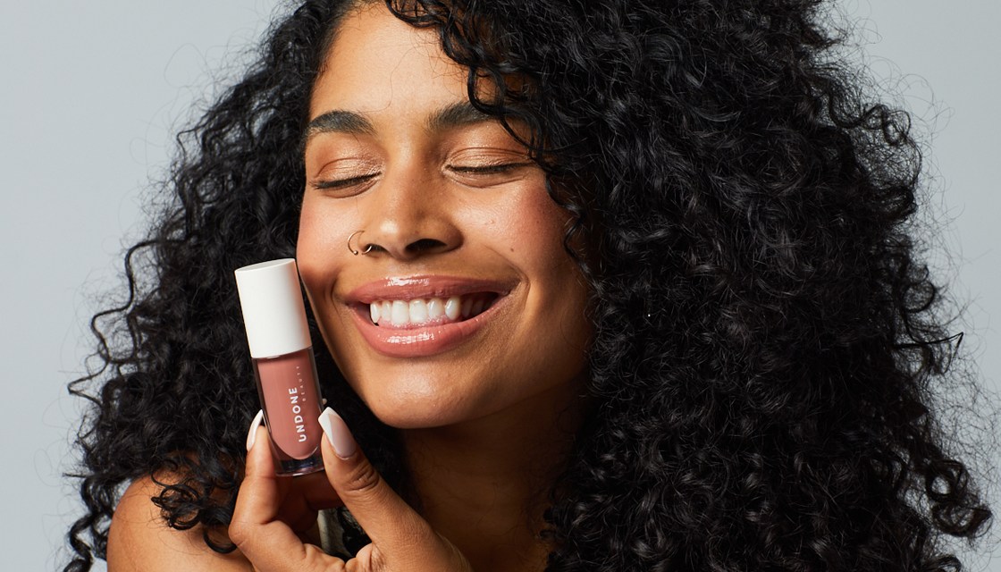 A woman holds an Undone Beauty product close to her face