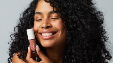 A woman holds an Undone Beauty product close to her face