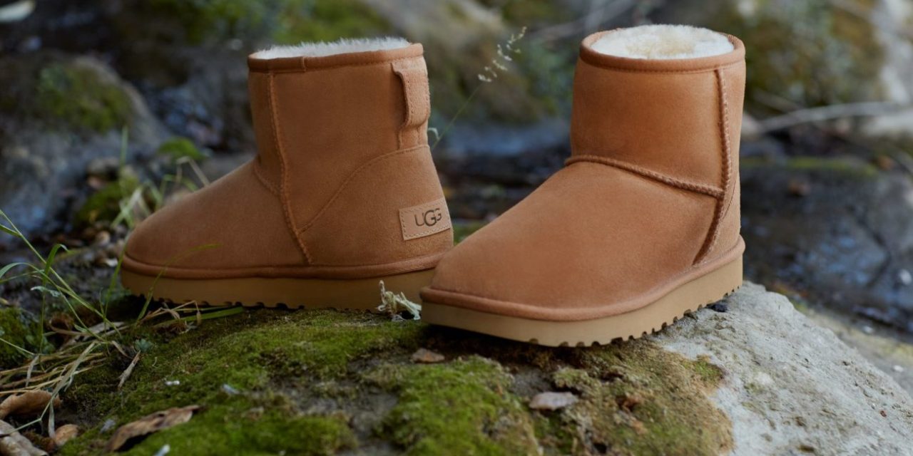 A pair of short fuzzy chestnut-colored boots posed outside on a rock.