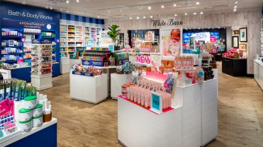 A Bath & Body Works store split into two sections; a Bath & Body Works section and a White Barn section, with displays featuring candles, soaps and other scented goods.