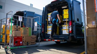A driver loads the back of an Amazon truck.