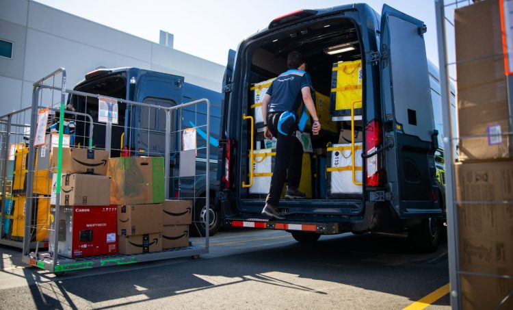 A driver loads the back of an Amazon truck.