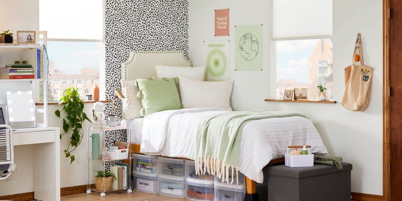 A twin bed with white bedding above containers in small dorm room.