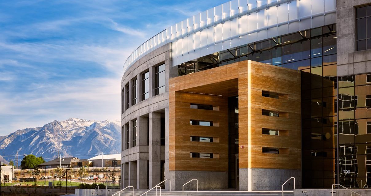 A large round building in front of a mountain scape and blue sky.