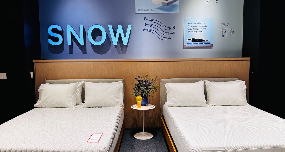 Two white mattresses side by side in a Casper store, underneath a sign that reads "snow technology"