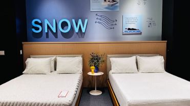 Two white mattresses side by side in a Casper store, underneath a sign that reads "snow technology"
