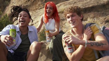 Three people drinking White Claw's Tequila Smash on a rock.