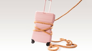 Pink rolling suitcase with a lasso attached around it