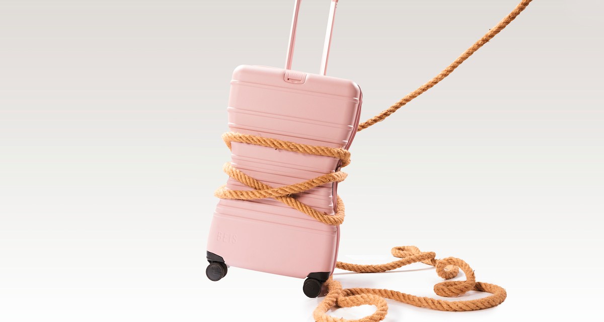 Pink rolling suitcase with a lasso attached around it