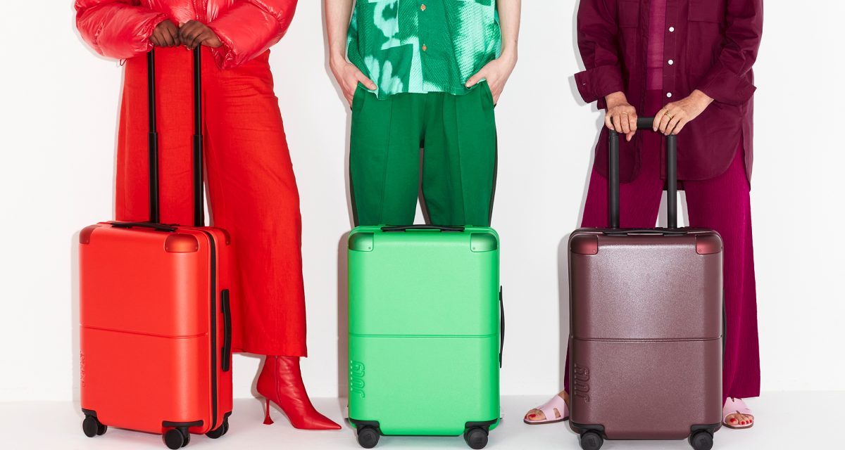 Three models displaying carry-on luggage in red, green and black shades