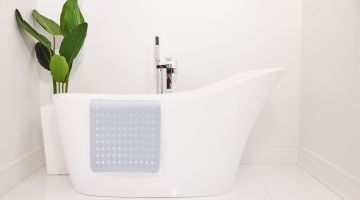 Silicon bath bat draped against a white bath tub