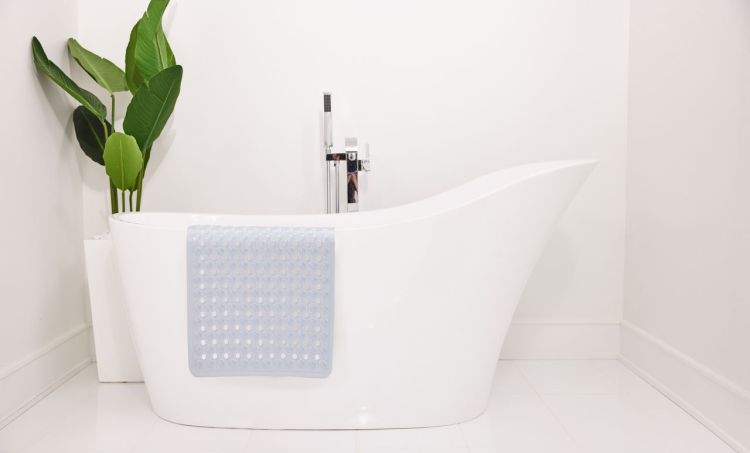 Silicon bath bat draped against a white bath tub